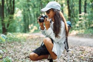 Using professional camera.. Girl ,is in the forest at summer day time discovering new places photo