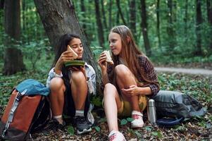 Sitting and eating.. Two girls is in the forest, having a leisure activity, discovering new places photo