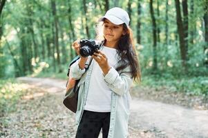 Using professional camera. Girl is in the forest at summer day time discovering new places photo
