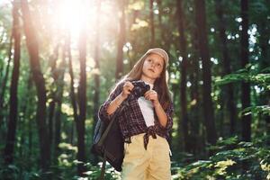 Young photographer with camera. Girl, is in the forest at summer day time discovering new places photo