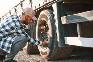 Testing the tires. Young, truck driver is with his vehicle at daytime photo