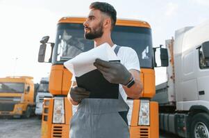Holding notepad. Quality control. Man in unifrom doing service for big truck vehicle. photo