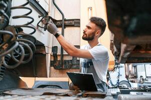 Looking at wires connection. Safety check. Man in unifrom doing service for big truck vehicle photo