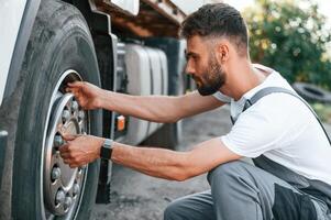 Changing the tire. Man in unifrom doing service for big truck vehicle photo