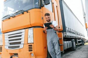 Holding notepad. Man in unifrom doing service for big truck vehicle photo