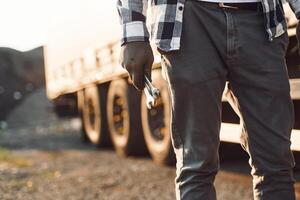 Close up view. .Young truck driver is with his vehicle at daytime photo