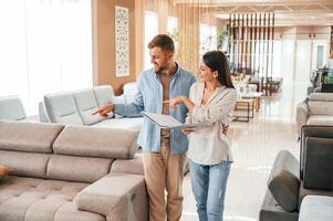 Talking with each other.. Couple choosing the sofa and bed in the store photo