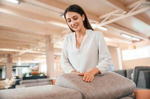 Touching the smooth surface. .Woman is visiting bed store. Looking for comfortable sofa photo