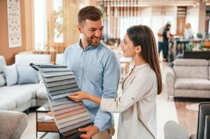 Man holding ,different colored materials to choose from. Couple looking for the sofa and bed in the store photo