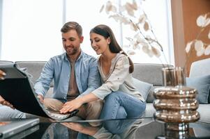 Looking at the, catalogue. Woman helping couple with choosing the sofa and bed in the store photo
