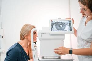 Side view. .Woman's vision is tested by clinic worker that using special device photo