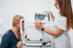 Side view. .,Woman's vision is tested by clinic worker that using special device photo