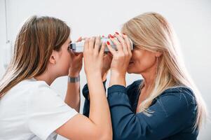 Woman's, vision is tested by clinic worker that using special device photo