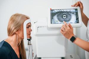 Side view. Woman's vision is tested by clinic worker that using special device photo