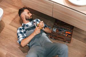 Plumber in uniform is indoors at home photo