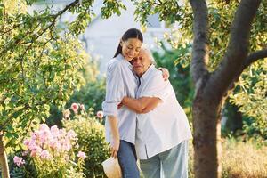 Time, for a hugs. Young woman ,is with her senior mother is in the garden photo