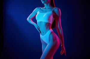 Taking, a closer look. Young woman in underwear is in the studio with neon lights photo