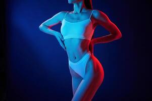 Taking a closer look.. Young woman in underwear is in the studio with neon lights photo