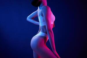 Side view. Young woman ,in underwear is in the studio with neon lights photo