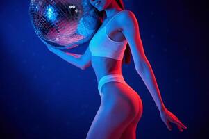With shiny mirrored ball.. Young woman in underwear is in the studio with neon lights photo