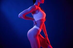 Side ,view. Young woman ,in underwear is in the studio with neon lights photo