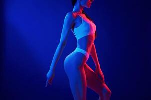 Side view. Young, woman in underwear is in the studio with neon lights photo