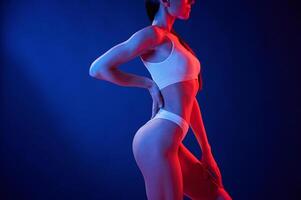 Blue, and red colors. Young woman in underwear is in the studio with neon lights photo