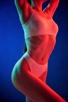 Illuminated, by red color. Young woman ,in underwear is in the studio with neon lights photo