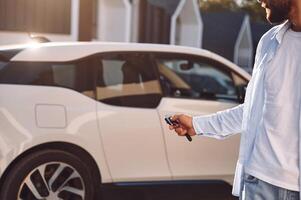 Locking the vehicle. Young stylish man is with electric car at daytime photo