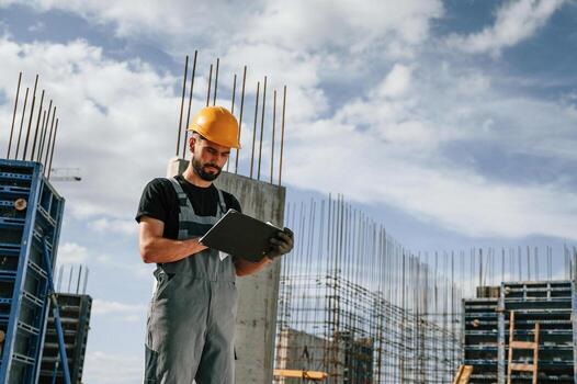 Control of the process. Foreman is with documents. Man in uniform is working on the construction site photo