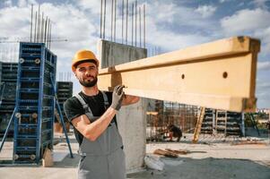 Front view.. Carrying ,wooden plank. Man in uniform is working on the construction site photo