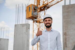 Smiling and, showing thumb up. Man in uniform is working on the construction site photo