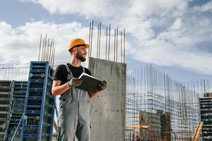 In ,hard hat, with notepad. Man in uniform is working on the construction site photo