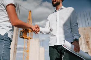 Doing handshake. Successfu,l agreement. Man in uniform working with woman on the construction site photo