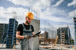 Control of the, process. Foreman is with documents. Man in uniform is working on the construction site photo