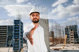 Engineer ,extends his hand. Man in uniform ,is working on the construction site photo