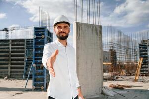 Enginee,r extends his hand. Man in uniform is working ,on the construction site photo