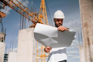Inspecting a plan. Man in uniform is working on the construction site photo