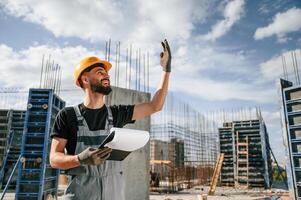Control ,of the process. Foreman is ,with documents. Man in uniform is working on the construction site photo