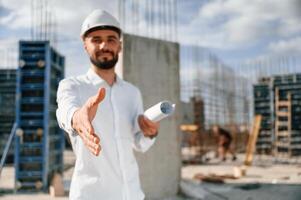 Engineer, extends his hand. Man in uniform is working on the construction site photo