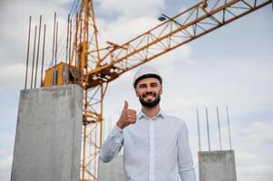 Smiling and showing thumb up. Man in uniform is working on the construction site photo