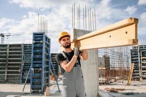 Carrying ,wooden plank. Man in uniform ,is working on the construction site photo