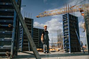 Standing with grinding machine in hands.. Man in uniform is working on the construction site photo