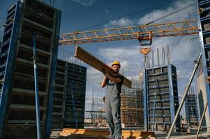 Yellow colored ,wooden plank. Man in uniform is working on the construction site photo
