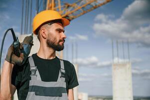Portrait of man that is, in uniform with the drill on the construction site photo