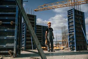 Standing, with grinding machine in hands.. Man in uniform is working on the construction site photo