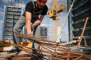 Metal, pieces covered in rust. Man in uniform is working on the construction site photo