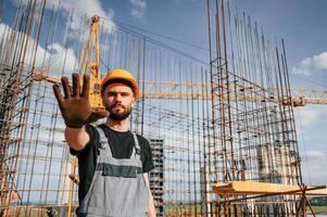 Closed area.. Stop gesture. Man in uniform is working on the construction site photo