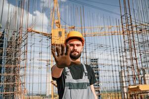 Closed, area. Stop gesture.. Man in uniform is working on the construction site photo