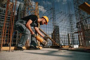 Using grinding machine to cut metal pieces. Man in uniform is working on the construction site photo